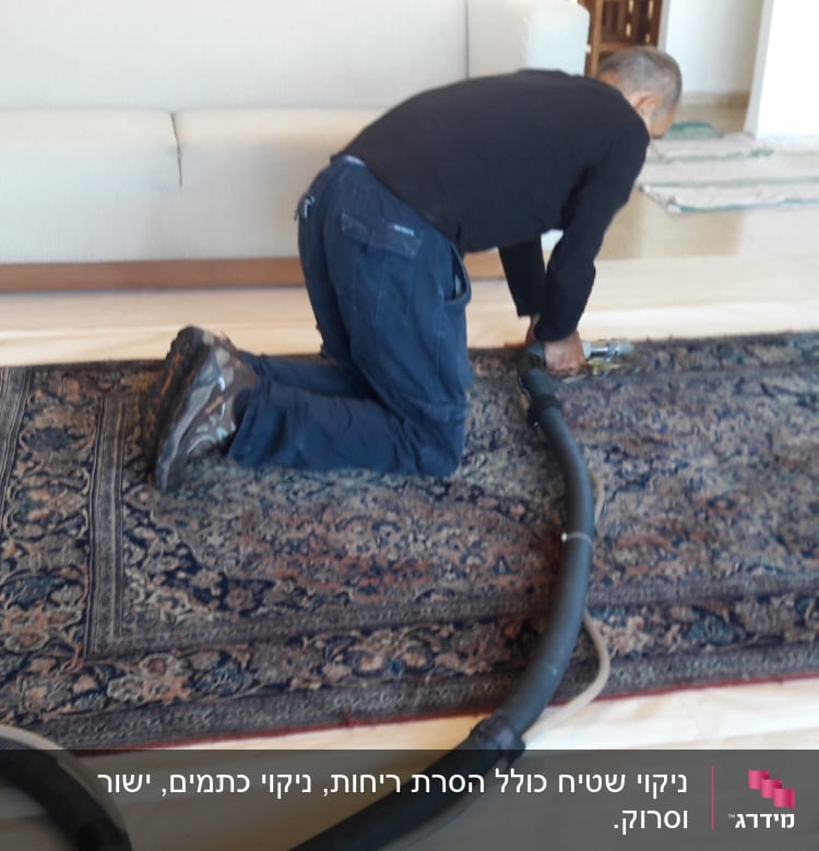אדם מנקה שטיח עם שואב אבק תעשייתי
